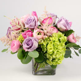 Pink and lavender flowers arranged in a clear glass vase