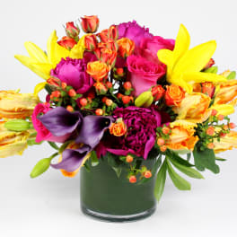 Bright mixed bouquet in a glass vase with roses, lilies, and calla lilies