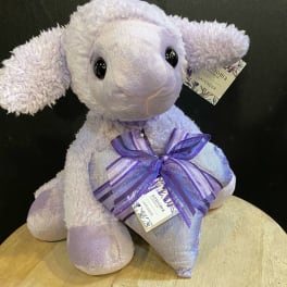 Lavender plush lamb holding a ribbon-tied pillow