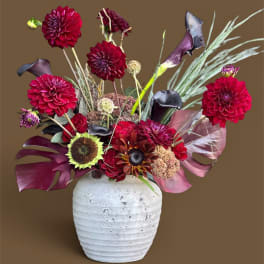 Red and purple floral arrangement in a white textured vase