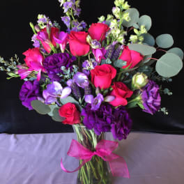 Bouquet of pink and purple flowers in a glass vase with a ribbon