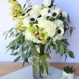 White roses and green orchids in a glass vase
