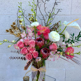 Pink roses and white calla lilies in a glass vase with a ribbon