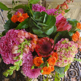 Mixed bouquet with pink hydrangeas, orange roses, and a red protea