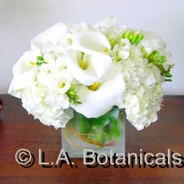 White calla lilies and hydrangeas in a square glass vase