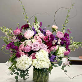 Mixed pink, purple, and white flowers arranged in a glass vase