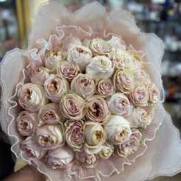 Bouquet of pale pink and cream roses wrapped in lace-like paper