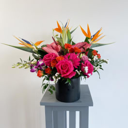 Bright tropical bouquet with pink roses in a black vase