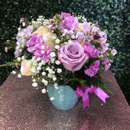 Pink and lavender bouquet in a blue vase with a ribbon