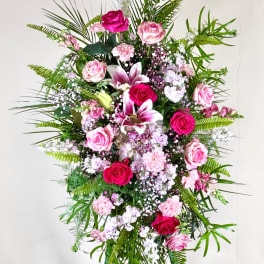 Tall standing floral spray with pink roses, lilies, and carnations on an easel