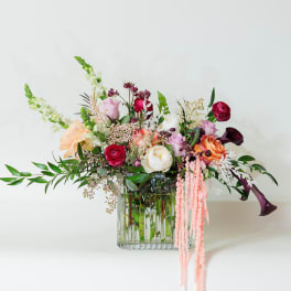 Mixed floral arrangement in a clear glass vase with pink, white, and burgundy blooms