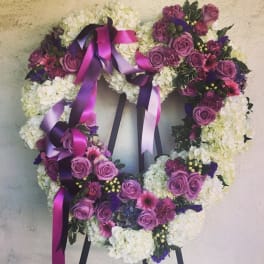Heart-shaped floral wreath with purple roses and white blooms, tied with magenta ribbons