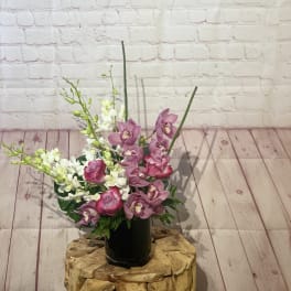 Pink orchids and roses arranged in a black vase