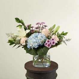 Mixed bouquet with blue hydrangea, lilies, and pink flowers in a glass vase