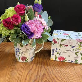 Mixed bouquet in a floral mug beside a matching gift box