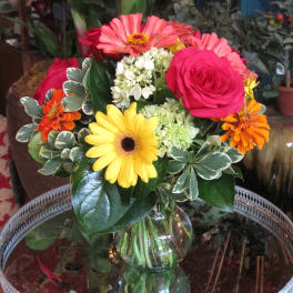 Mixed bouquet of roses, gerbera daisies, and hydrangea in a glass vase