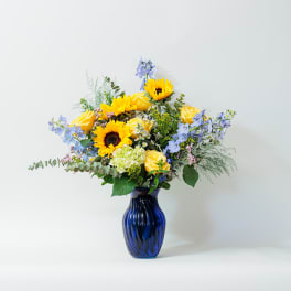 Yellow sunflowers and roses in a blue glass vase