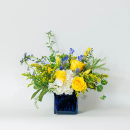 Yellow and blue floral arrangement in a dark blue vase