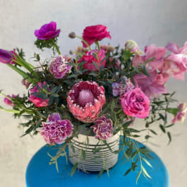 Pink and purple mixed bouquet in a striped container