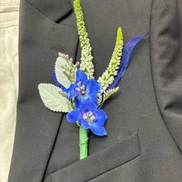 Blue boutonniere with white spikes pinned to a black suit jacket
