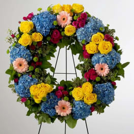 Colorful floral wreath with blue hydrangeas, yellow roses, and pink gerbera daisies