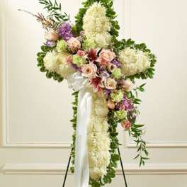 Standing floral cross with white and pastel flowers on a white ribbon