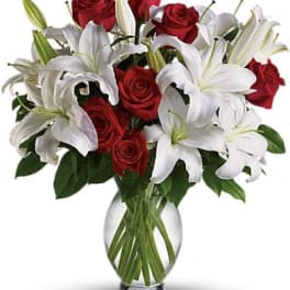 Red roses and white lilies arranged in a clear glass vase