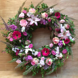 Circular floral wreath with pink roses, lilies, and magenta daisies