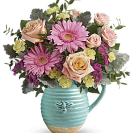 Pink gerberas and peach roses in a turquoise pitcher vase