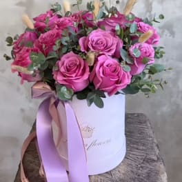 Pink roses arranged in a white hat box with a ribbon