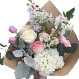 Hand-tied bouquet of pink and white flowers wrapped in brown paper