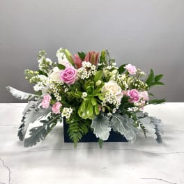 Pink and white floral arrangement in a rectangular container