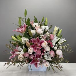 Pink and white lilies and roses arranged in a low rectangular vase