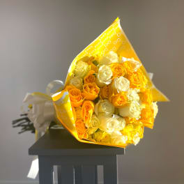 Bouquet of yellow and white roses wrapped in bright yellow paper
