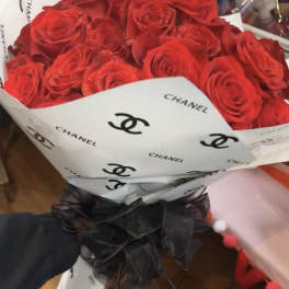 Bouquet of red roses wrapped in white Chanel paper with a black ribbon