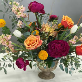 Mixed bouquet of roses, peonies, and tulips in a pedestal vase