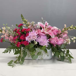 Pink floral arrangement in a rectangular white vase