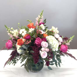 Mixed pink, orange, and white flowers in a glass vase