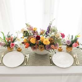 Floral table centerpiece with roses and mixed blooms on a dining table