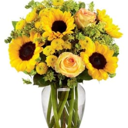 Sunflowers and peach roses arranged in a clear glass vase