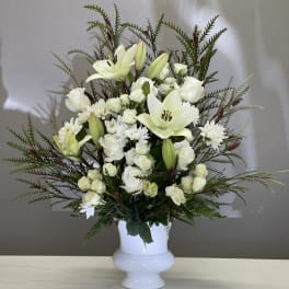 White lilies and roses arranged in a white vase