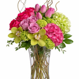Pink roses and tulips in a clear glass vase with green hydrangeas