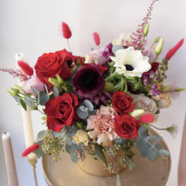 Mixed bouquet of red, white, and pink flowers in a gold vase