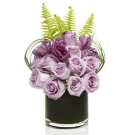 Lavender roses in a black glass vase with green fern fronds