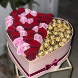 Heart-shaped box with red and pink roses and gold-wrapped chocolates