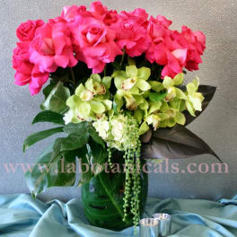 Pink roses and green orchids arranged in a glass vase