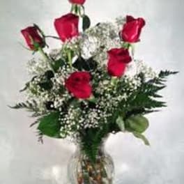 Red roses arranged in a clear glass vase with baby's breath