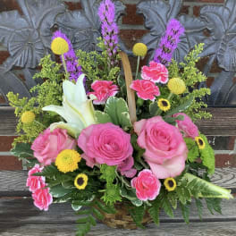 Basket arrangement with pink roses, white lilies, and yellow accents