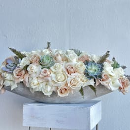 Low arrangement of pale roses and succulents in a shallow bowl