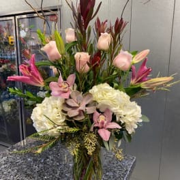 Tall mixed floral arrangement in a clear glass vase with pink and white blooms